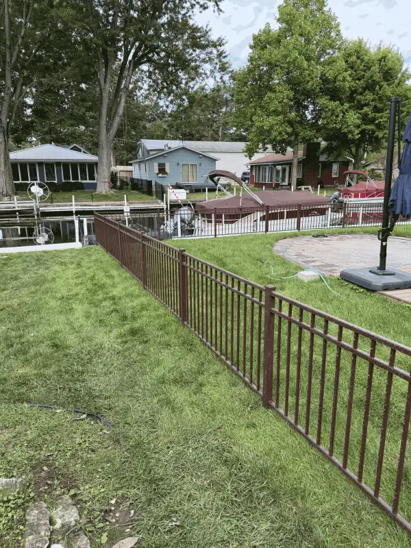 Black aluminum ornamental fence along lakefront yard with dock and boats, Northern Indiana installation