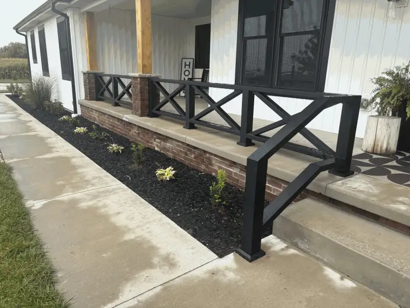 Black aluminum X-brace porch railing on brick knee wall, corner view, Northern Indiana installation