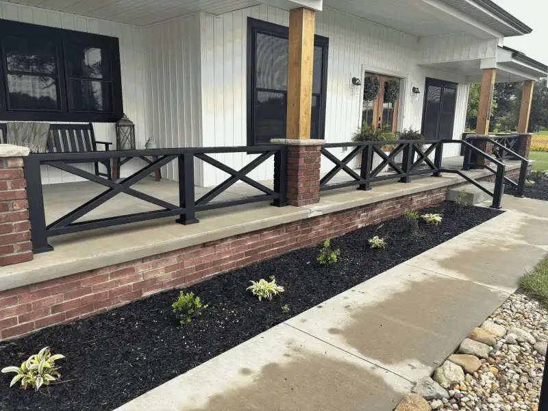 Black aluminum X-brace porch railing wrapping around farmhouse porch, Northern Indiana installation