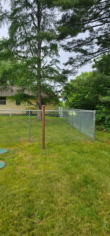 Chain link fence with corner post and gate, wooded residential yard in Northern Indiana
