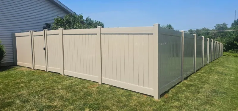 Tan vinyl privacy fence corner view beside house, Northern Indiana installation