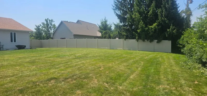 Tan vinyl privacy fence enclosing large backyard, Northern Indiana installation